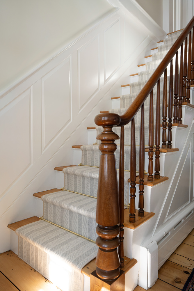 classic custom staircase with detailed railing and paneled walls by Craft Design + Build in Lyme, CT