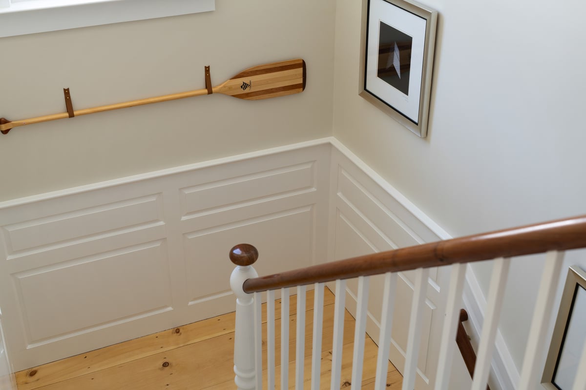 custom home stair landing with wood railing and wall paneling by Craft Design + Build in Durham, CT
