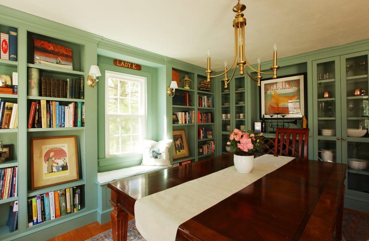 Bright dining room with green built-in bookcases in a remodeled Essex, Connecticut home by Craft Design + Build