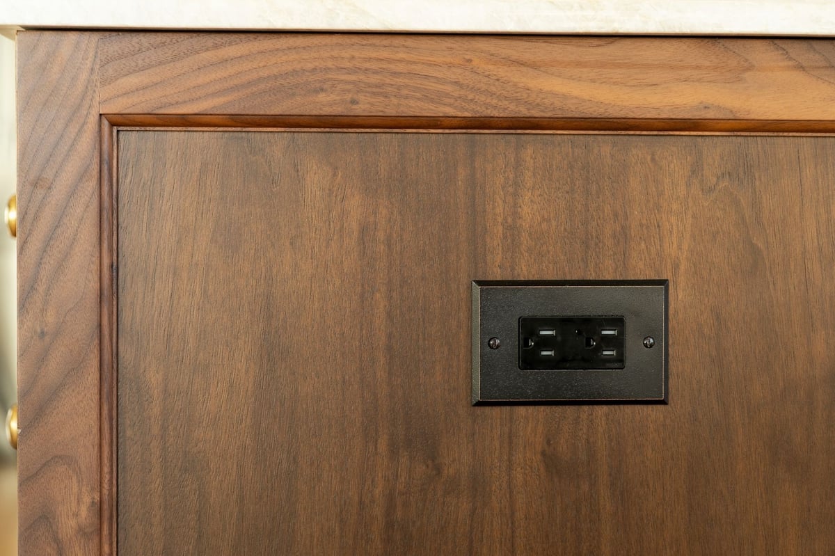 brushed nickle electrical outlet cover on a wooden kitchen island