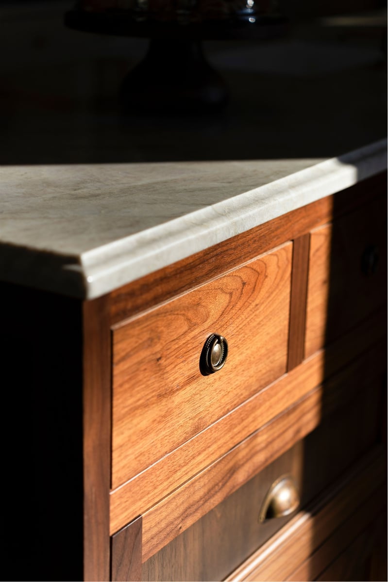 natural light on a traditional wooden kitchen island with marble countertops