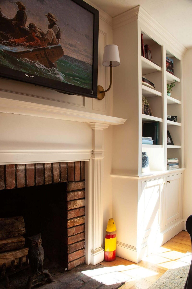 Close-up of a brick fireplace and custom shelving in an Essex, Connecticut remodel by Craft Design + Build