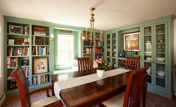 Dining room featuring built-in green bookshelves in a remodeled Essex, Connecticut home by Craft Design + Build