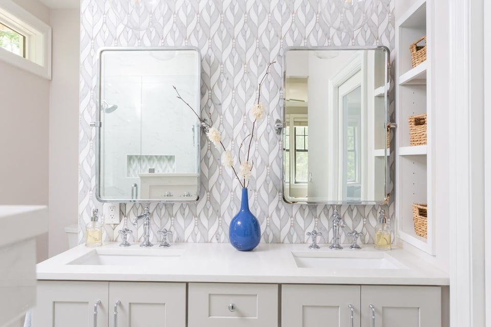 Elegant owners bathroom featuring dual sinks and a stylish patterned backsplash, remodeled by Craft Design + Build in Essex, Connecticut