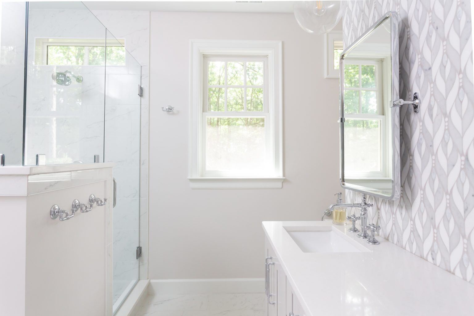 Elegant owners bathroom featuring dual sinks and a stylish patterned backsplash, remodeled by Craft Design + Build in Essex, Connecticut-1