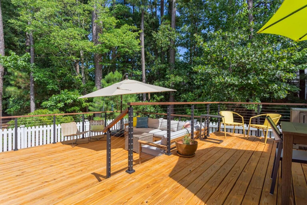 Elevated deck in Essex, Connecticut, remodeled by Craft Design + Build, featuring outdoor seating and lush greenery