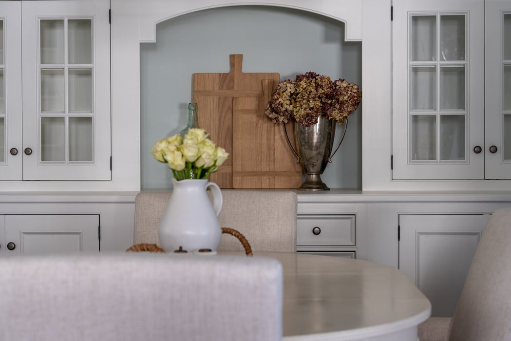 Dining area with white cabinets and floral decor by Craft Design Build in Essex, CT