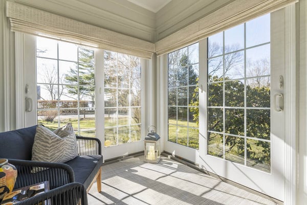 Sunroom with black chairs and garden view through large windows by Craft Design Build in Essex, CT