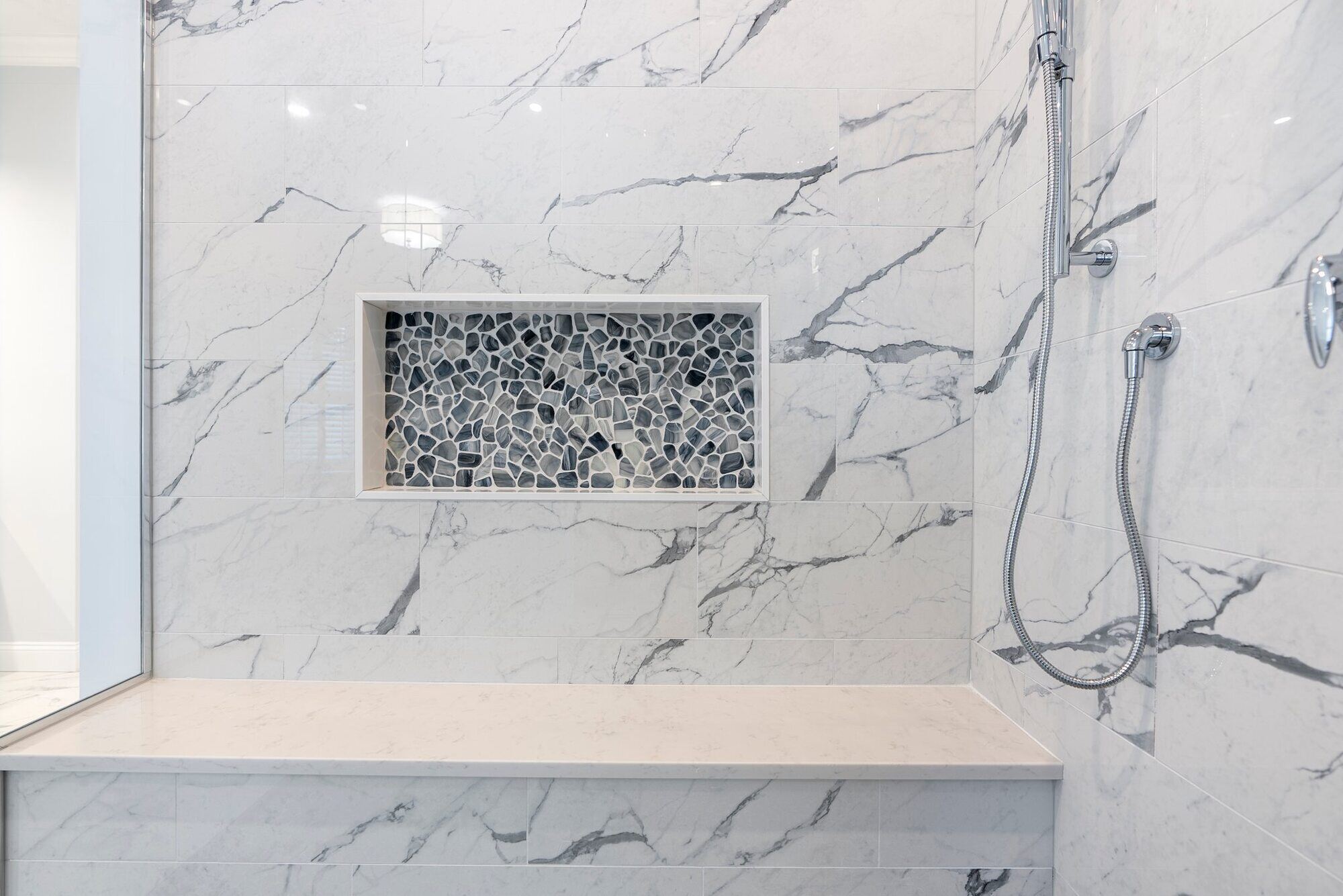 Marble shower with built-in bench and niche by Craft Design Build in Essex, CT