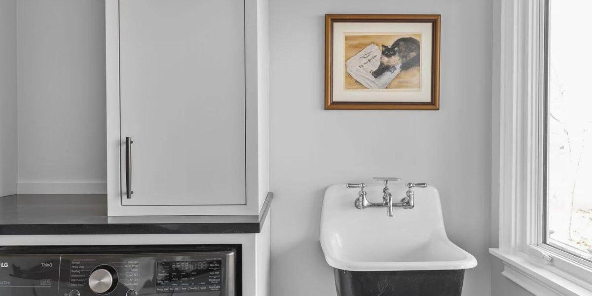 Functional Essex laundry room featuring white cabinets and sink, remodeled