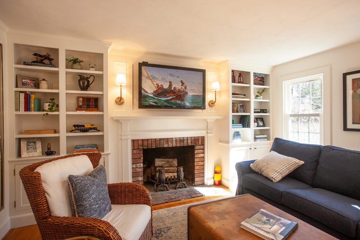Remodeled Essex, Connecticut living room with a cozy fireplace and custom shelving by Craft Design + Build