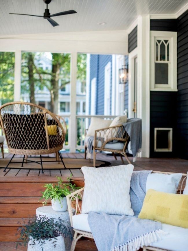 Stylish porch with wicker furniture and wooden flooring in an Essex, Connecticut historical home renovation by Craft Design + Build