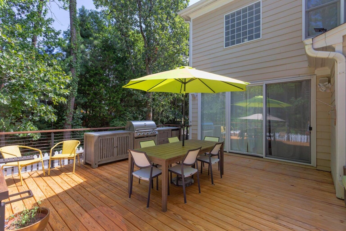 Two-level deck renovation by Craft Design + Build in Essex, Connecticut, featuring seating areas and lush greenery