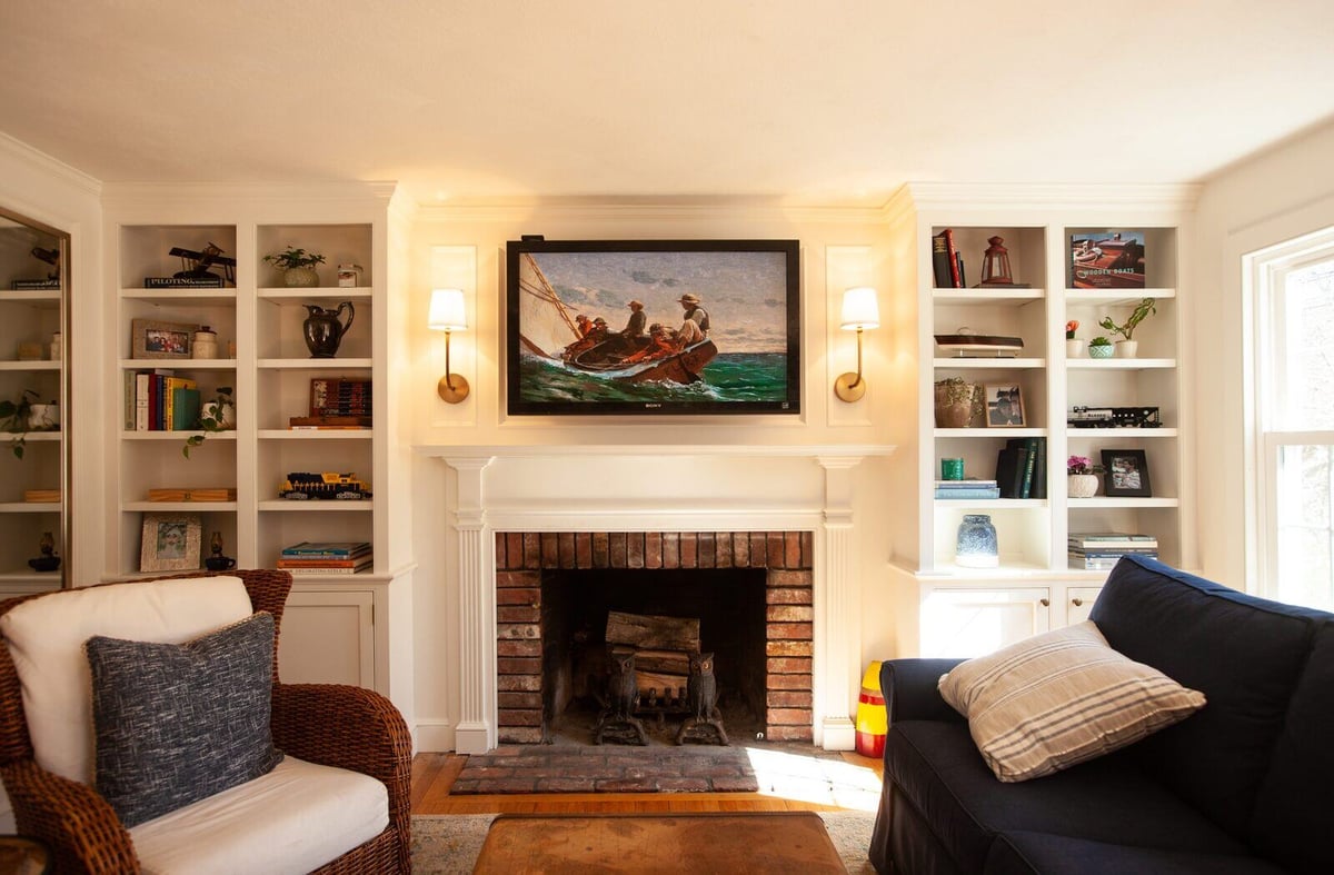 Warm and inviting living room with a brick fireplace and custom shelving in Essex, Connecticut, remodeled by Craft Design + Build