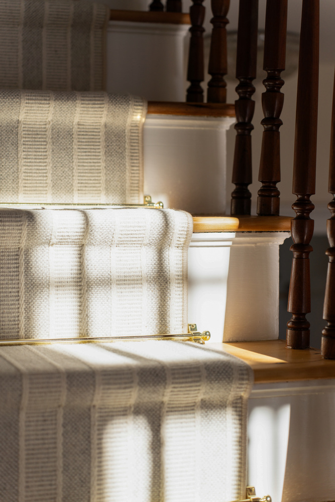 close-up of custom staircase runner and wood railing detail by Craft Design + Build in Deep River, CT