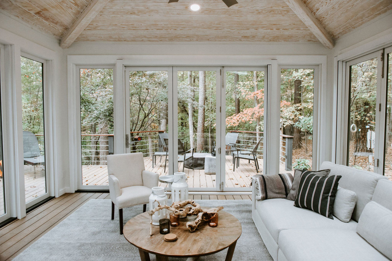 Cozy sunroom with large windows and deck access, designed by Craft Design + Build, Essex, Connecticut
