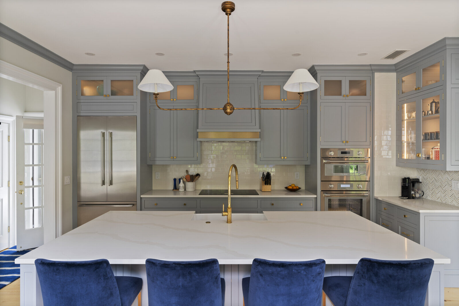 Spacious kitchen in Essex, Connecticut remodeled by Craft Design and Build, featuring grey cabinets and blue chairs