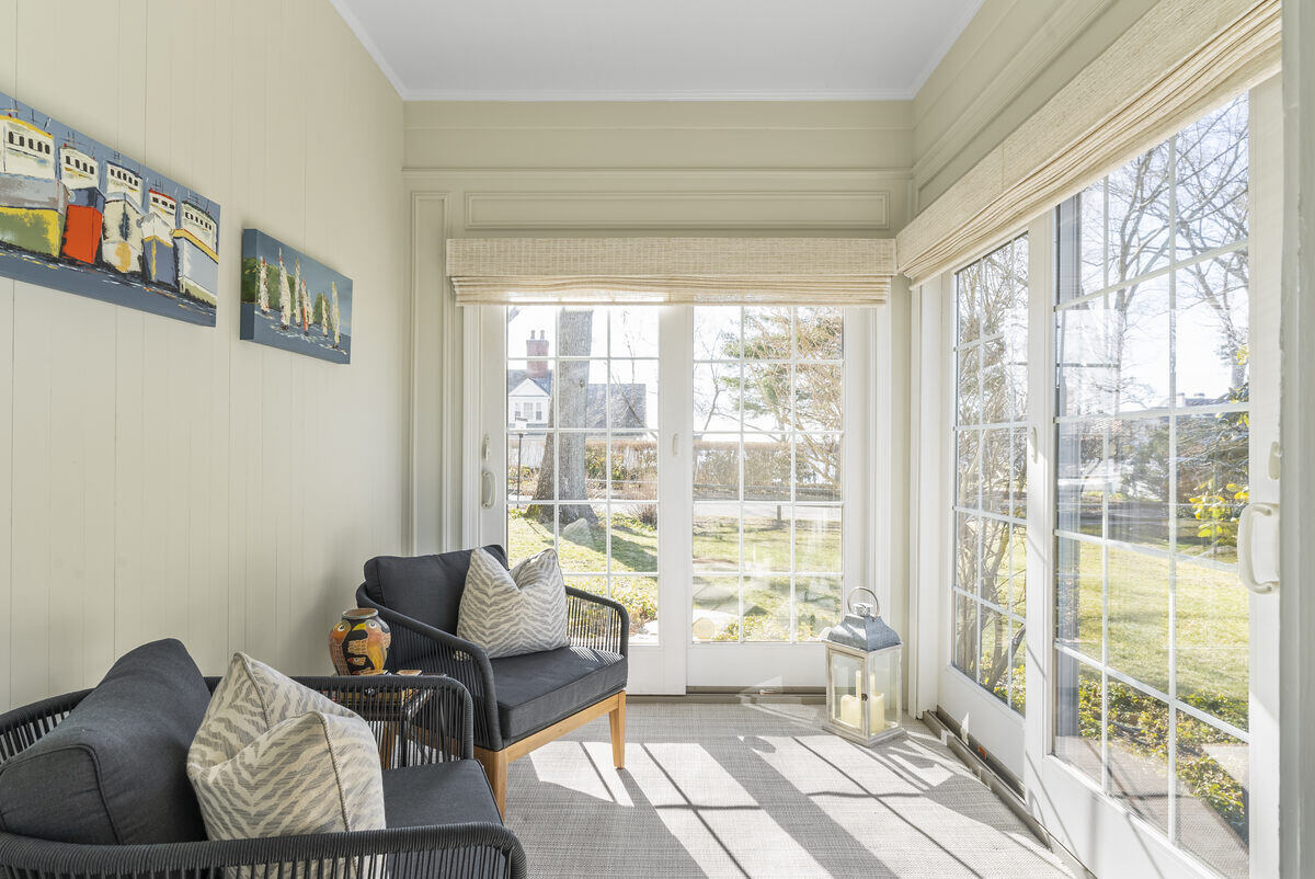 Bright sunroom with black chairs and nautical-themed wall art by Craft Design Build in Essex, CT