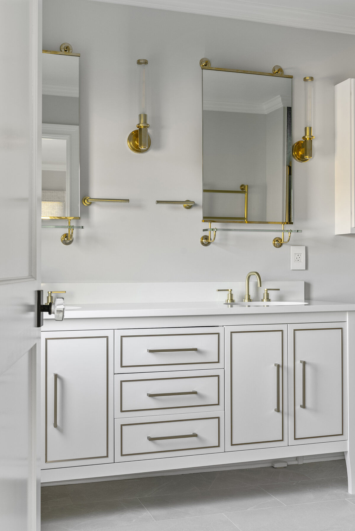 Close-up of gold faucet and mirror in a modern bathroom by Craft Design Build in Essex, CT