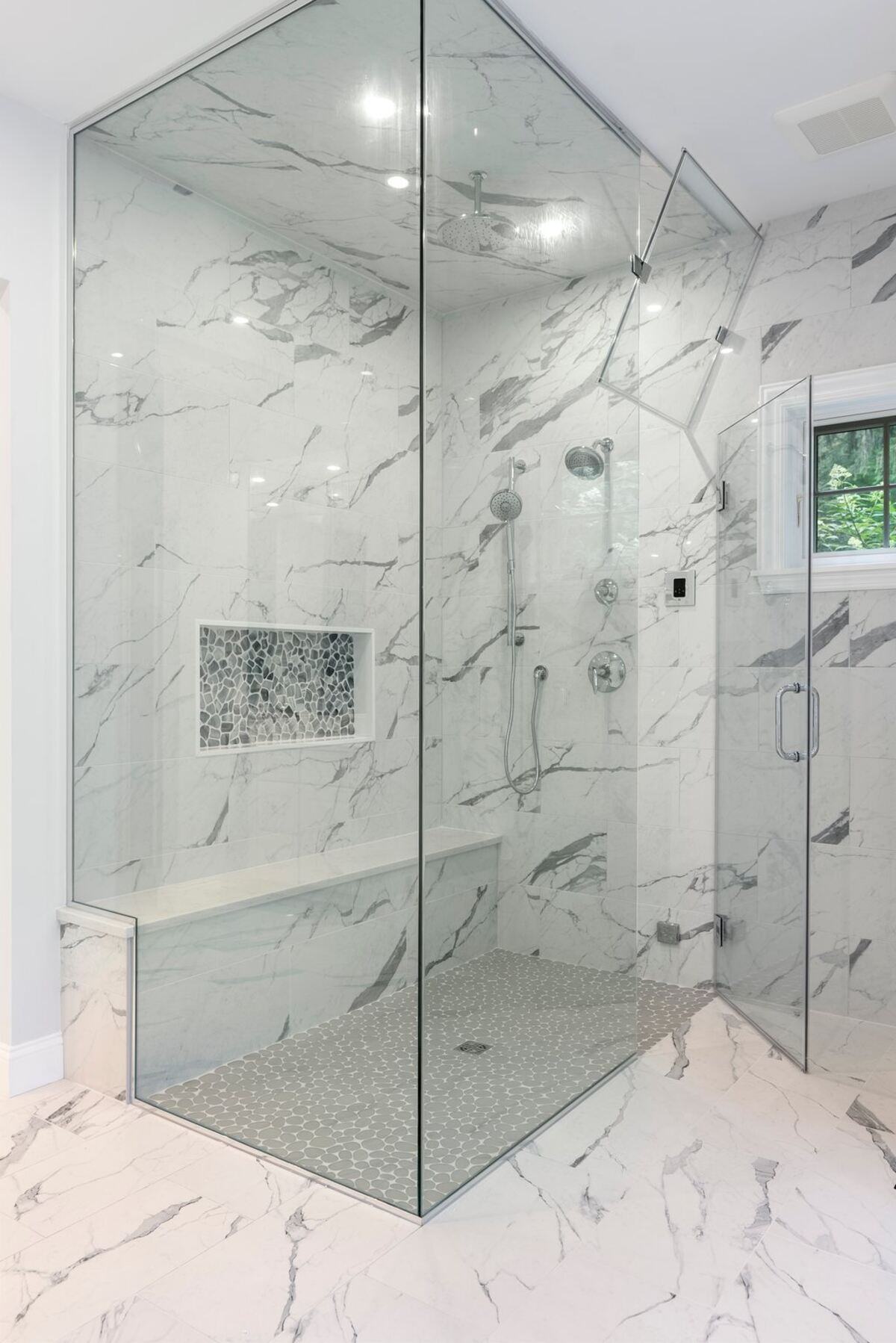 Modern glass-enclosed shower in a marble bathroom remodel by Craft Design Build in Essex, CT