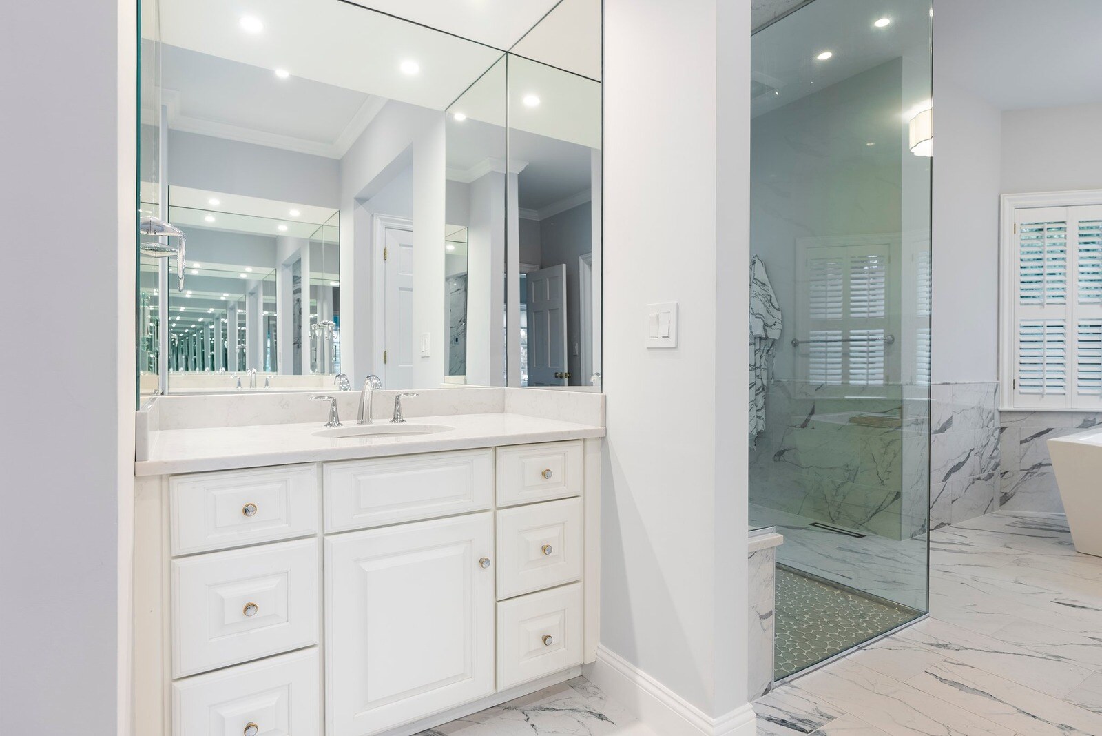 Bright white bathroom featuring a modern vanity and expansive mirrors, remodeled by Craft Design Build in Essex, CT