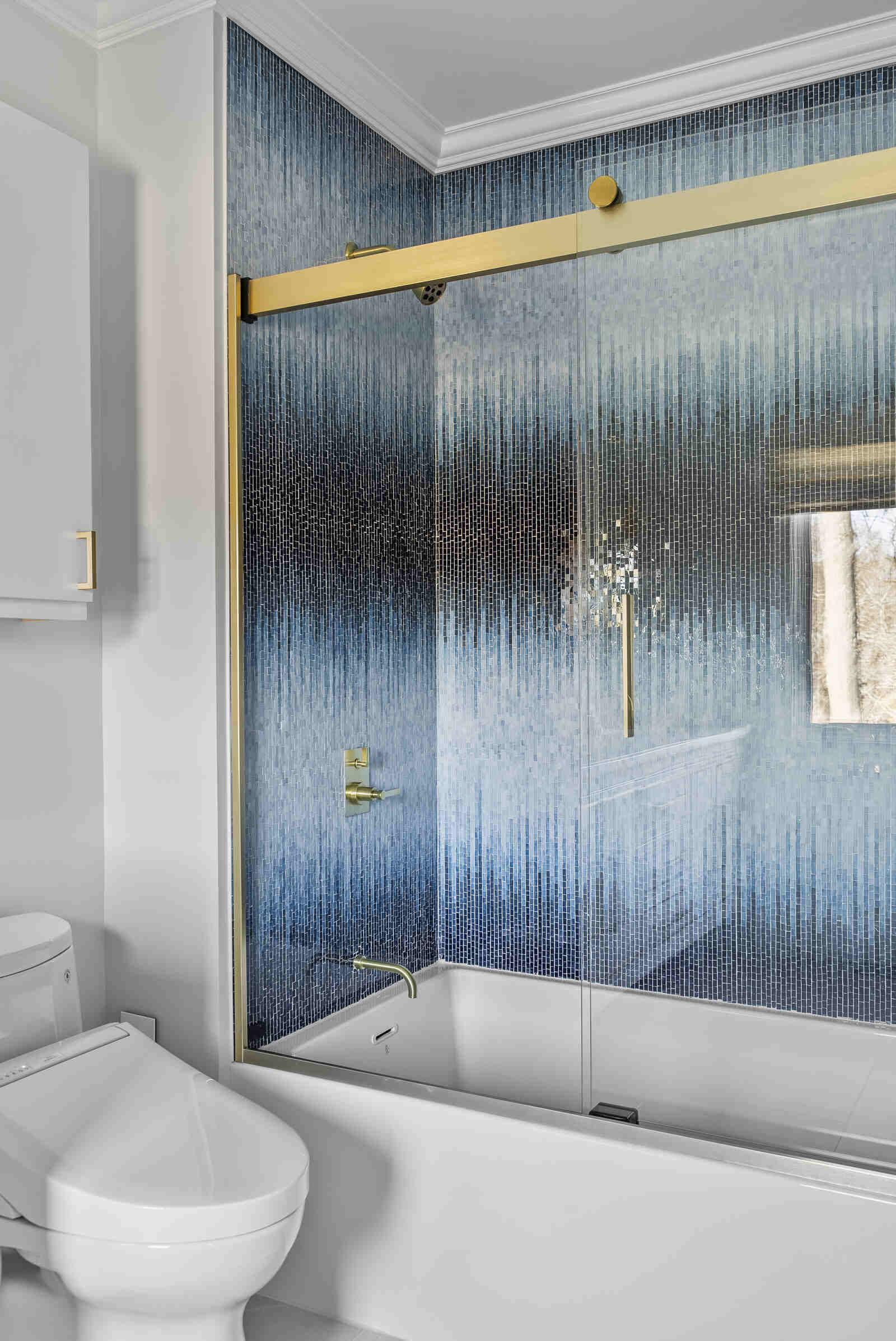 Elegant bathroom remodel by Craft Design Build in Essex, CT with gold fixtures and blue mosaic tiles